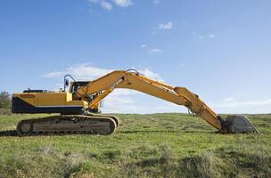 geel graafmachine Aan veld- foto