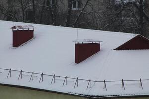 daken en schoorstenen gedekt met sneeuw in winter foto