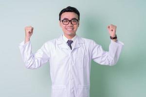 Aziatische arts die zich op groene achtergrond bevindt foto