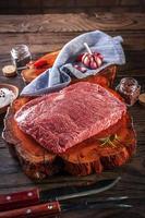 rauw marmer denver rundvlees op een houthars snijplank met kruiden en barbecuevork en mes. foto