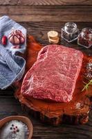 rauw marmer denver rundvlees op een houthars snijplank met kruiden en rozemarijntak. foto
