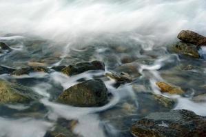 turbulentie zeewater en rots aan de kust foto