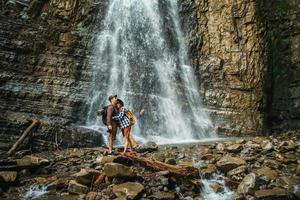 man en vrouw wandelaars wandelen een rotsachtig pad tegen de achtergrond van een waterval en rotsen foto