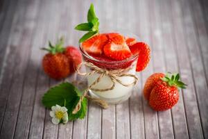 zoet eigengemaakt yoghurt met aardbei jam en vers aardbeien in een glas kop foto