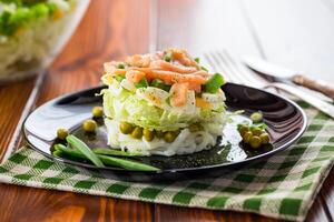 gelaagde salade van kool en andere groenten met stukken van rood vis in een bord. foto