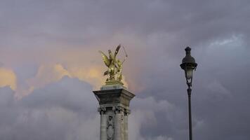 Frankrijk, Parijs - juli 24, 2022. gouden standbeeld Aan toren Aan achtergrond van wolken. actie. mooi landschap met gouden beeldhouwwerk Aan achtergrond van kleurrijk avond wolken. gouden standbeeld van Alexander foto