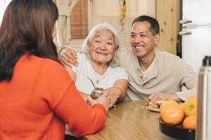 gelukkig volwassen kinderen sharing met hun ouderen Japans moeder drinken maat in de keuken. foto