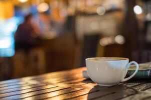 heet latte koffie kop Aan houten tafel en gloeiend bokeh vervagen achtergrond foto