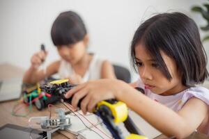 inventief kinderen leren Bij huis door codering robot auto's en elektronisch bord kabels in stang. construeren robot auto's Bij huis foto