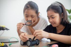 inventief kinderen leren Bij huis door codering robot auto's en elektronisch bord kabels in stang. construeren robot auto's Bij huis foto