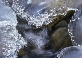 een dichtbij omhoog van ijs en water vloeiende door een stroom foto