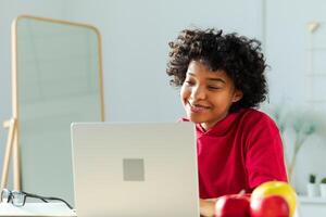 Afrikaanse Amerikaans meisje gebruik makend van laptop Bij huis kantoor op zoek Bij scherm typen chatten lezing schrijven e-mail. jong vrouw hebben virtueel vergadering online babbelen video telefoontje conferentie. werk aan het leren van huis foto