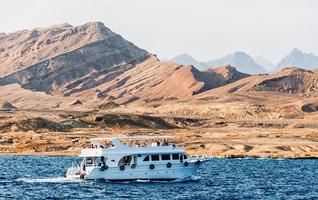 sharm el sheikh, egypte, 2021 - witte cruiseboot in de buurt van de rotsachtige kust foto