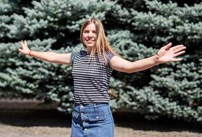 jonge, mooie blanke vrouw in vrijetijdskleding die plezier heeft in het ronddraaien op de bontachtergrond in het park foto