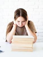 depressief schoolmeisje met een stapel boeken foto