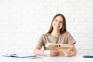 gelukkig lachend tiener schoolmeisje met een stapel boeken foto