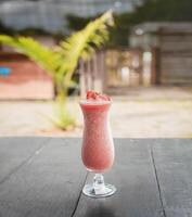 dichtbij omhoog van gezond aardbei smoothie Aan hout met wazig achtergrond, aardbei smoothie Aan houten tafel. aardbei milkshake Aan houten tafel met wazig achtergrond foto