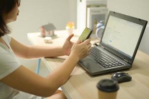 een vrouw die thuis werkt met een smartphone. foto