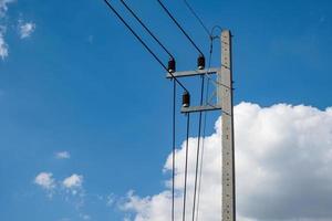 elektriciteitsbetonpaal en hoogspanningsdraad bij hemelachtergrond foto