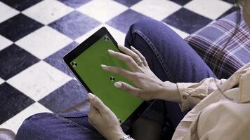 vrouw Bij huis ontspannende en op zoek Bij haar tablet computer met groen scherm Aan de verdieping van zwart en wit kleur. voorraad filmmateriaal. zwart tablet met chroma sleutel in de handen van een brunette meisje. foto