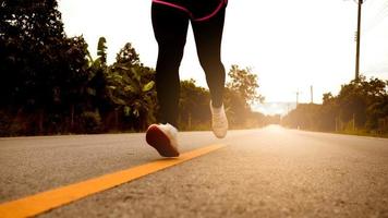 vrouwelijke hardlopers lopen op het pad in de ochtendtraining voor marathon en fitness. gezond levensstijlconcept. atleet die buiten traint. close-up benen. foto