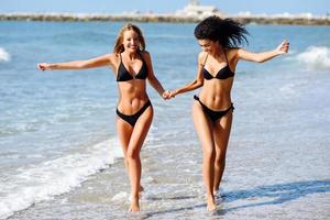 twee jonge vrouwen met mooie lichamen in badkleding op een tropisch strand foto