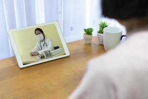 senior patiënt die koorts en hoest kreeg, raadpleeg een aziatische arts over medicatie via een videogesprek. telegeneeskunde en nieuw normaal levensstijlconcept foto