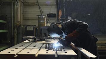 professioneel zwaar industrie arbeider lasser in beschermend masker en pak werken met metaal bouw Aan fabriek. creatief. staal en ijzer lassen bouw plaats, lassen machine met vonken en foto