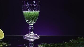 groen drinken met ingrediënten is gegoten in glas. voorraad klem. helder groen drinken met gassen is gegoten in transparant glas. alcoholisch drinken met ingrediënten Aan tafel in bar foto