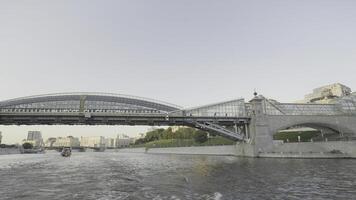 visie van drijvend boot Aan stad rivier- met glas brug. actie. mooi panorama van rivier- Aan achtergrond van stad en glas brug. modern geglazuurd brug Aan Doorzichtig zonnig dag foto