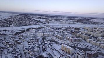 antenne visie van een groot stad met gebouw daken gedekt door sneeuw. klem. vliegend bovenstaand bevroren stad en een rivier. foto