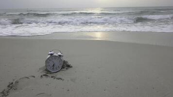 vakantie tijd. alarm klok Aan de zand. video. kijk maar de strand. kijk maar aan het liegen in de zand Aan de zee symboliseert een tijd van rust uit foto