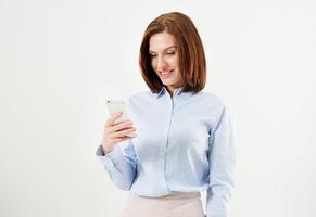 vrouw tekstbericht typen op slimme telefoon. afbeelding van een jonge vrouw die op een witte achtergrond staat met behulp van mobiele telefoon. foto