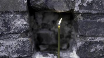 detailopname van een brandend kaars in een steen muur. filmmateriaal. kerk brandend kaars foto