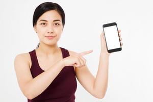 schattige koreaanse, aziatische vrouw vinger wijst naar een leeg scherm telefoon geïsoleerd op een witte achtergrond foto