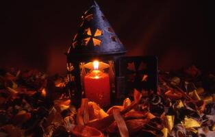een kaars is lit in een lantaarn omringd door bladeren foto