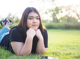 portret jong vrouw Aziatisch mollig schattig mooi een persoon slapen kijken hand- Holding gebruik spelen slim telefoon in tuin park buitenshuis avond zonlicht vers glimlachen vrolijk gelukkig kom tot rust zomer dag foto