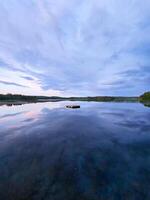 zwemmen eiland in Zweden Aan een meer Bij zonsondergang. wolken weerspiegeld in de water. foto