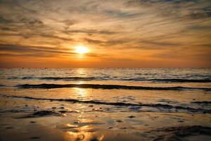 zonsondergang, verlichte zee. zanderig strand in de voorgrond. licht golven. Baltisch zee foto