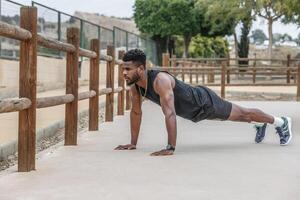 zwart sportman aan het doen plank oefening in park foto