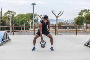 sterk sportman hijs- kettlebell in park foto