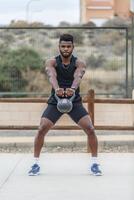 zwart sportman aan het doen kettlebell schommel oefening foto