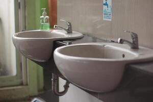 twee wastafel naar Azië openbaar toilet, twee modern keramisch wastafels, keramisch wastafel met chroom menger in hedendaags wasruimte. foto