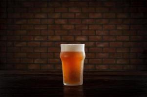 geïsoleerd bezweet glas verfrissend bier van de tap met bakstenen muur achtergrond. foto