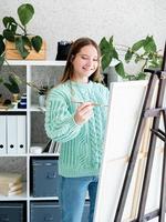 jonge lachende vrouw kunstenaar met kleurenpalet aan het werk in haar studio foto