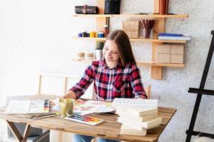 jonge lachende vrouw tekenen met waterverf in haar atelier