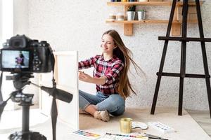 vrouw die een video maakt voor haar blog over kunst met behulp van een op een statief gemonteerde digitale camera foto