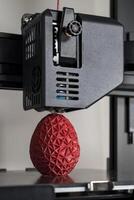 dichtbij omhoog van een 3d printer het drukken een rood veelhoekige ei foto