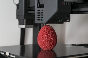 dichtbij omhoog van een 3d printer het drukken een rood veelhoekige ei foto