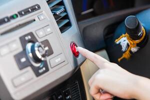 vrouw hand- drukken noodgeval licht knop Aan auto dashboard. foto